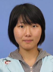 Huimei Liu mit kurzem schwarzen Haar und grauer Kapuzenjacke, vor blauem Hintergrund.